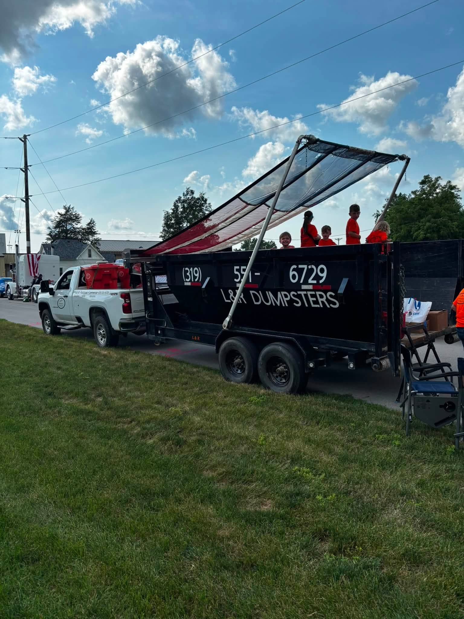 Red truck and black trailer with a solar panel canopy at an outdoor event on a grassy field