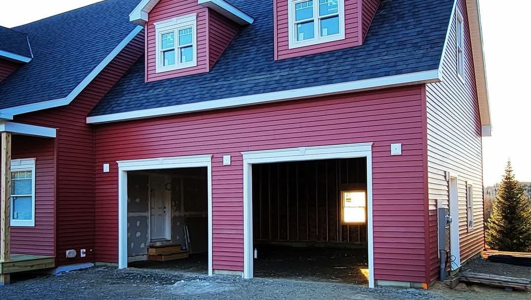 A red house with a garage underneath it