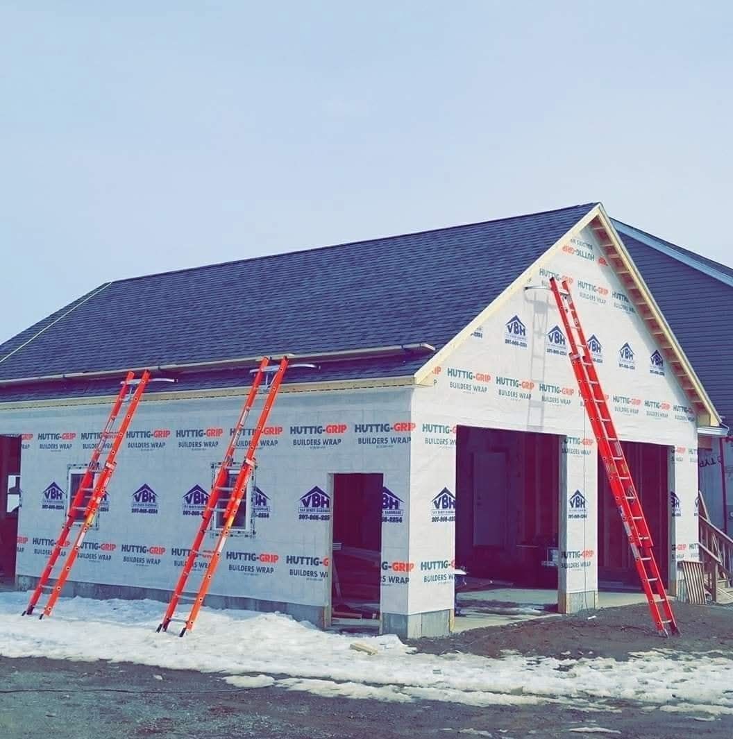 A garage is being built in the snow with ladders in front of it