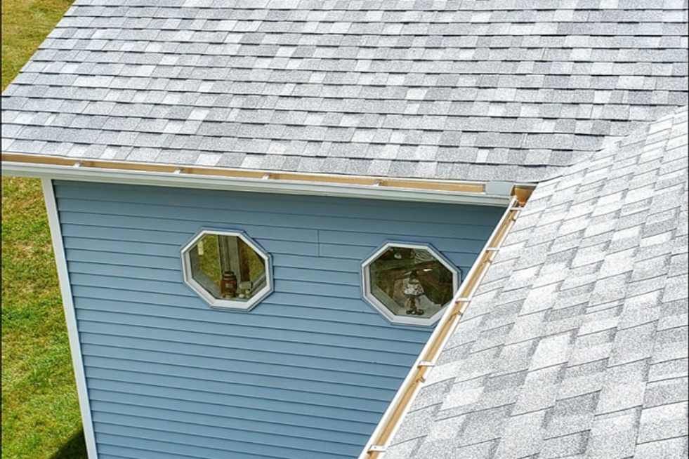 A blue house with a white roof and two windows on the side.