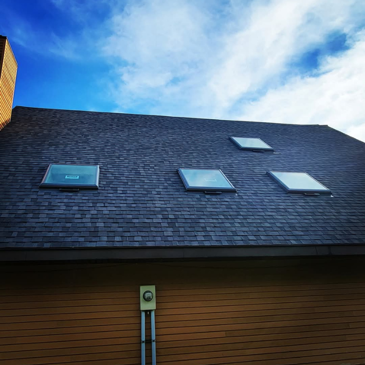 The roof of a house with three skylights on it.