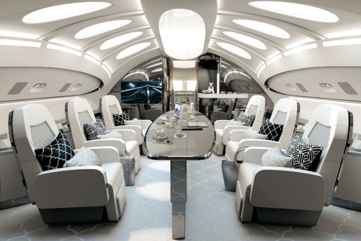 Luxurious private jet interior with white seating, oval table, and recessed lighting.