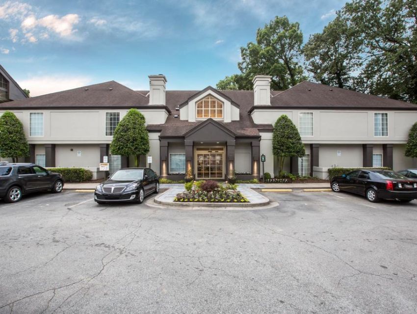 Large two-story brick townhouse complex with parked cars and a landscaped entrance courtyard
