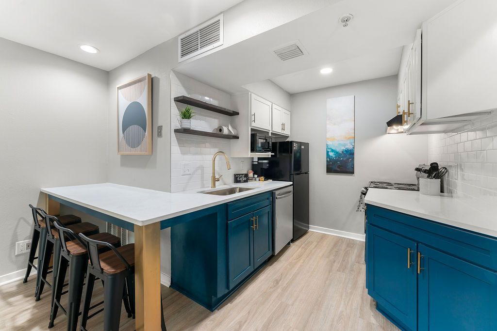 Bright modern kitchen with teal cabinets, island seating, and stainless steel appliances.
