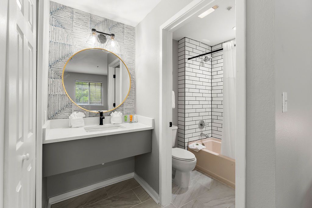 Modern bathroom vanity with round mirror and walk-in shower with black tile accents