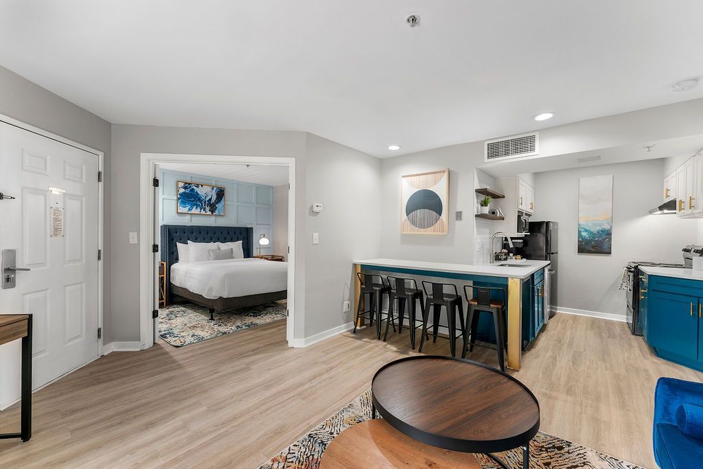 Modern open-concept living room and dining area with white walls, wood floors, blue accents, and a round coffee table