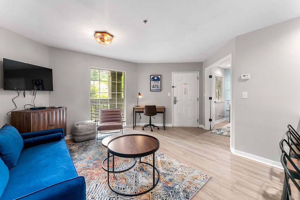 Bright living room with blue sofa, coffee table, desk, and sliding glass door to patio