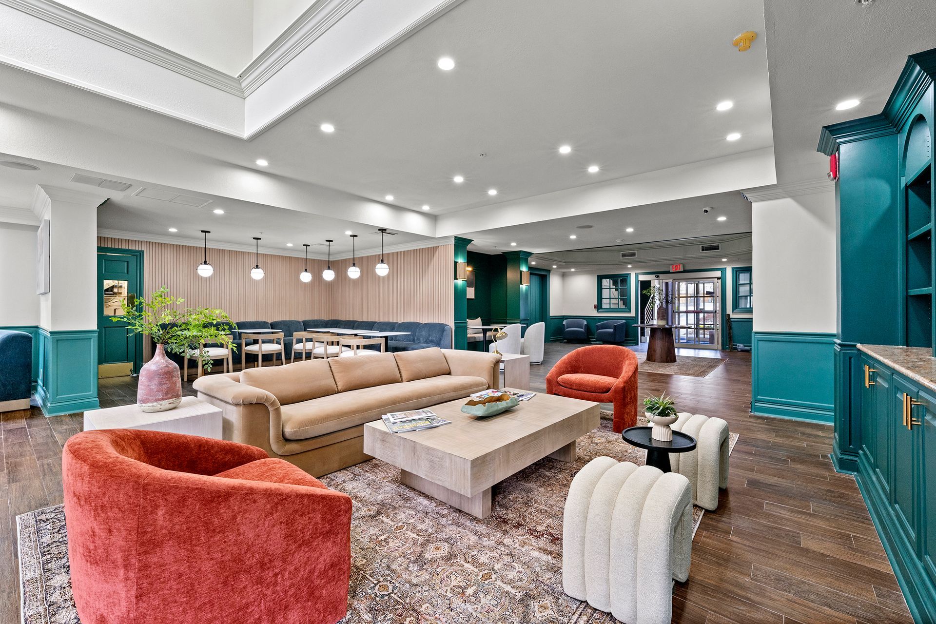 Modern hotel lobby with teal walls, beige and coral seating, and recessed ceiling lights