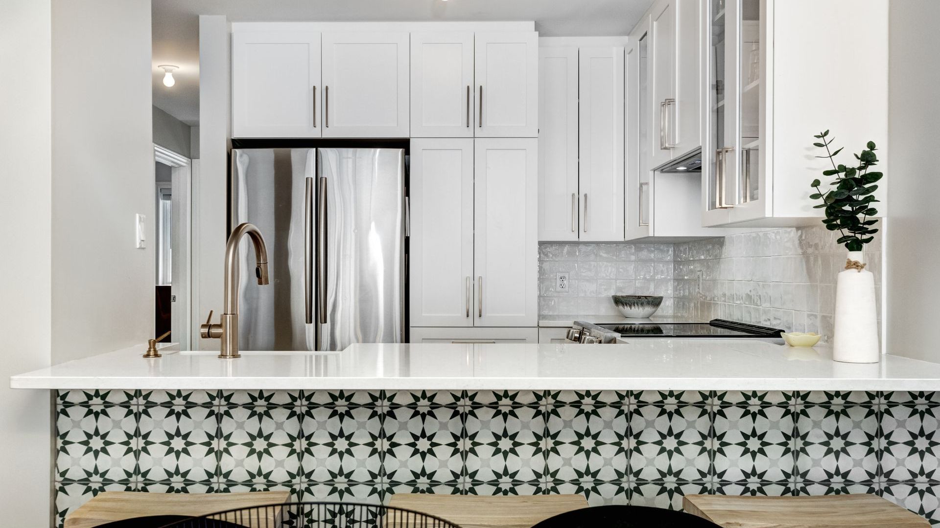 Bright modern kitchen with white cabinets, stainless steel fridge, and patterned tile island front