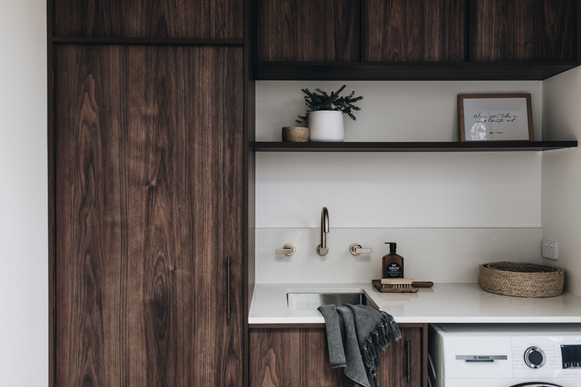 Laundry room with dark wood cabinets, white countertop, sink, and shelves with decor — Stark Building & Constructions In Kiama, NSW
