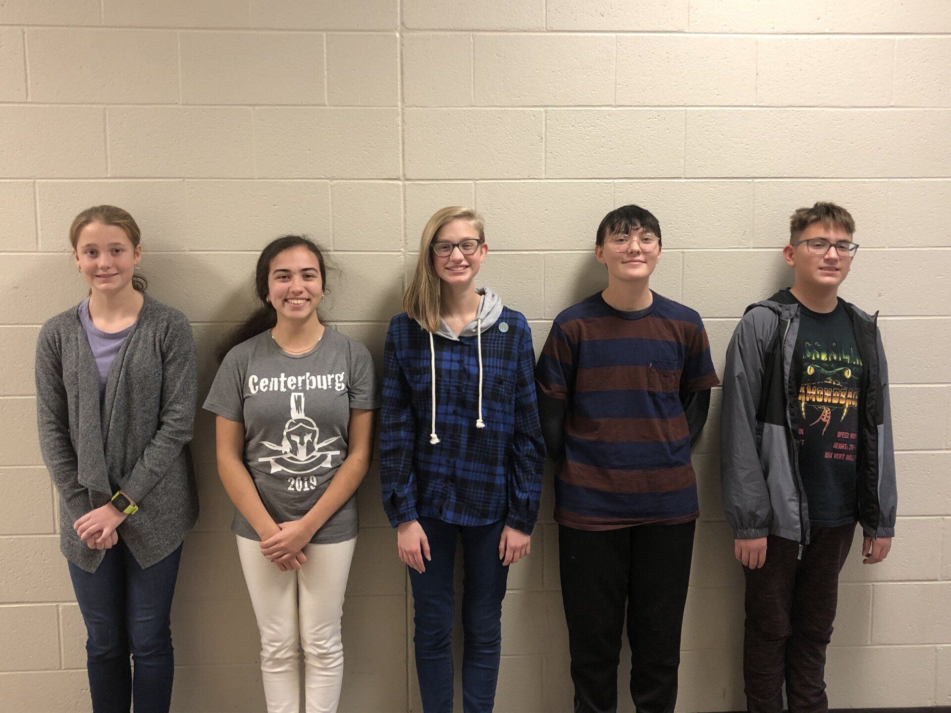 a group of young people are standing next to each other in front of a brick wall .