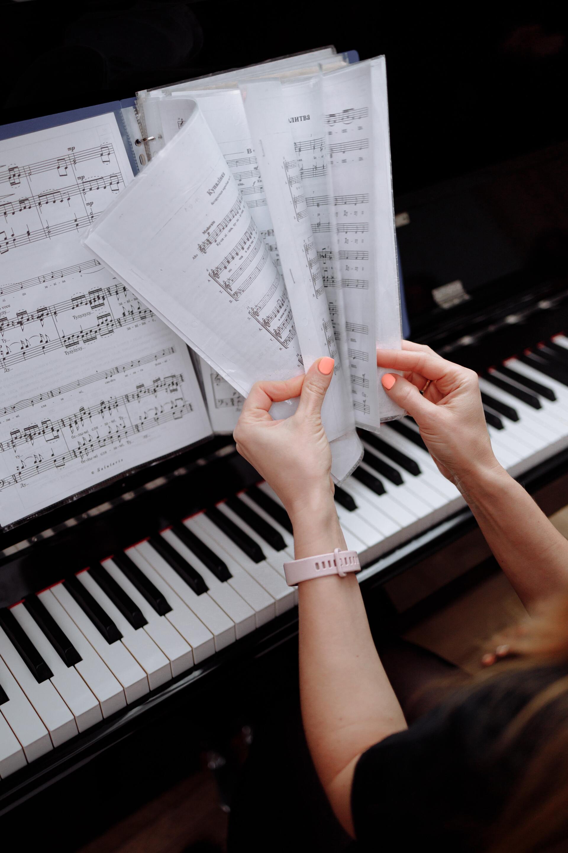 a person is holding sheet music in front of a piano .