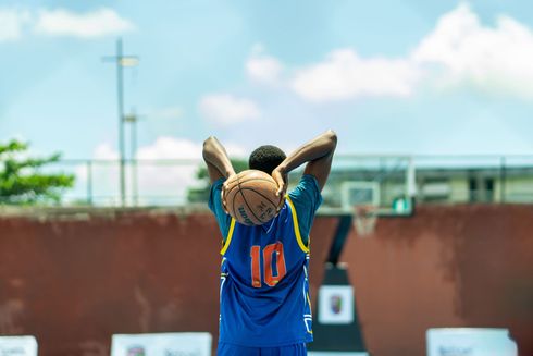 Basketball player in blue jersey number 10 preparing to throw the ball on an outdoor field
