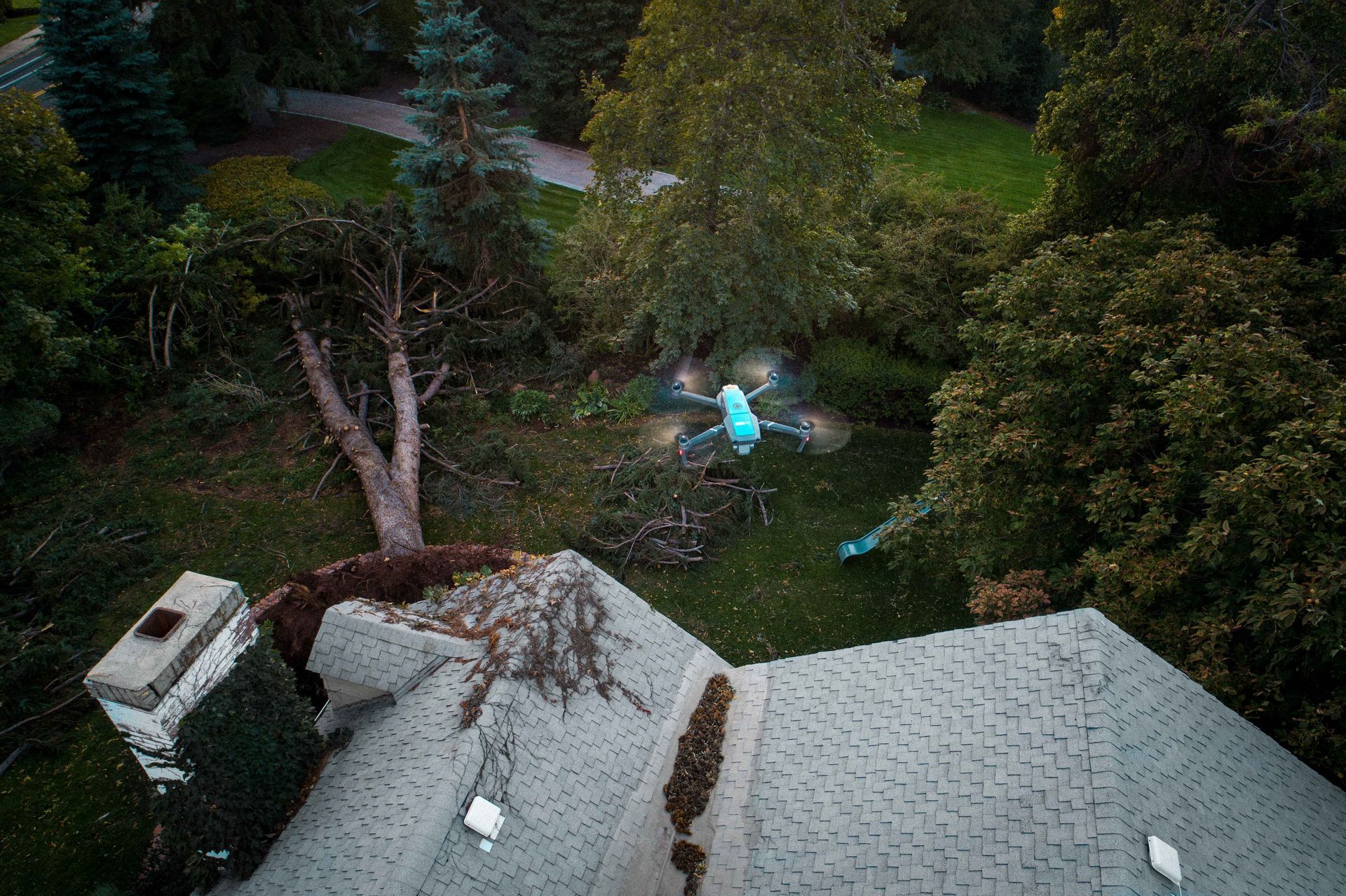 An aerial view of a house with a fallen tree on the roof.