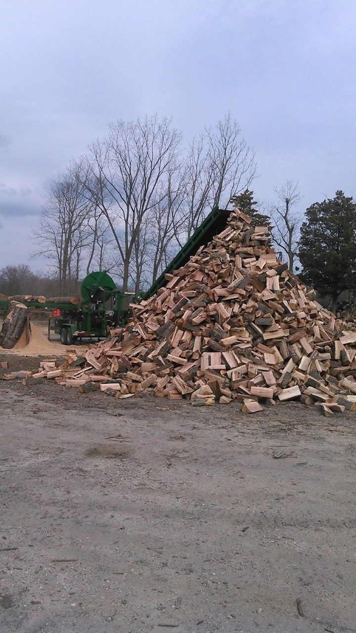 Pile of rubble and broken bricks beside a green machine in an open lot under a cloudy sky