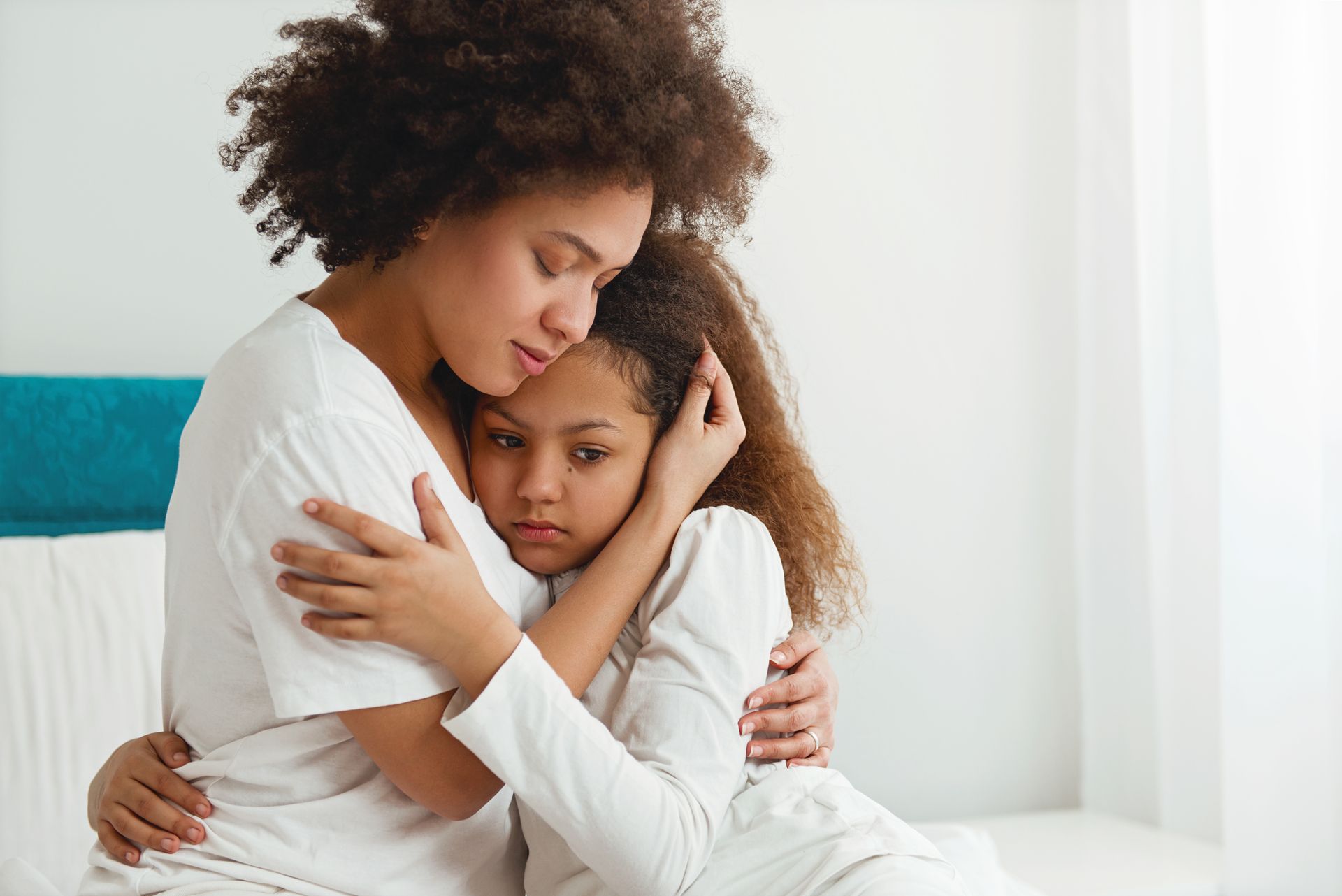 A woman is hugging a little girl in a park.
