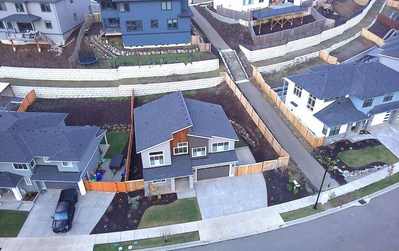 Aerial view of a suburban neighborhood with houses, driveways, and a curving street.