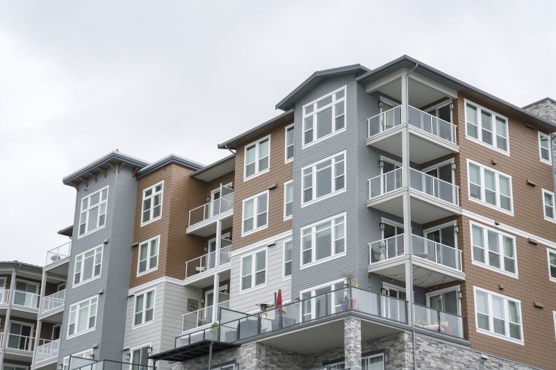 Modern apartment building with gray and brown siding, balconies, and large windows