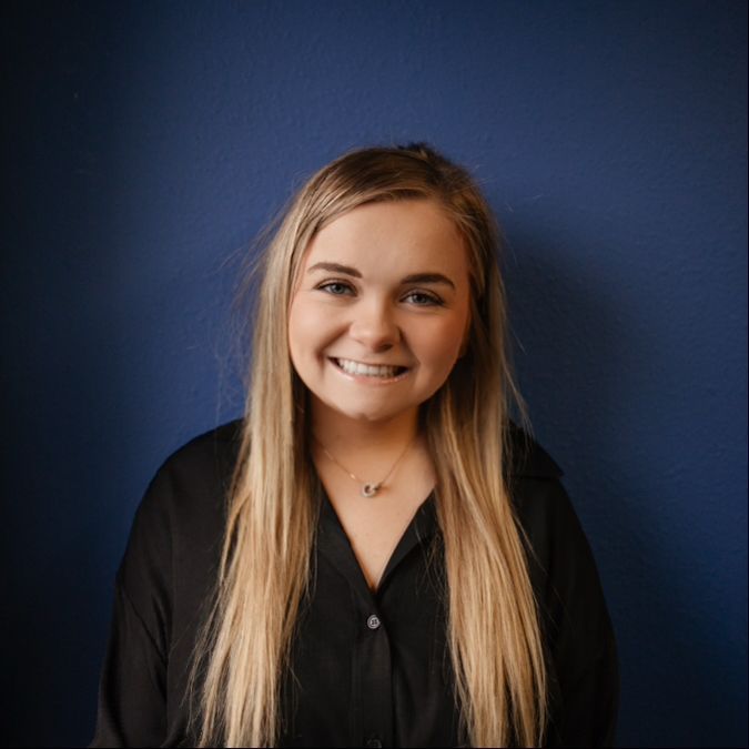 Smiling woman in a black blouse against a dark blue wall