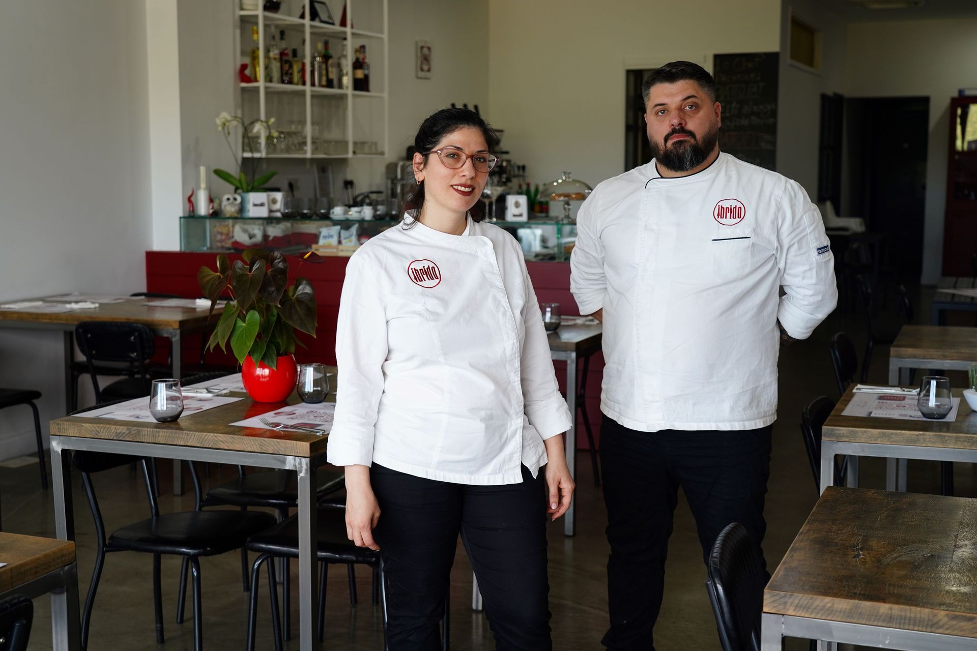Due persone in giacca da chef bianca in piedi su un piano di lavoro in cucina.
