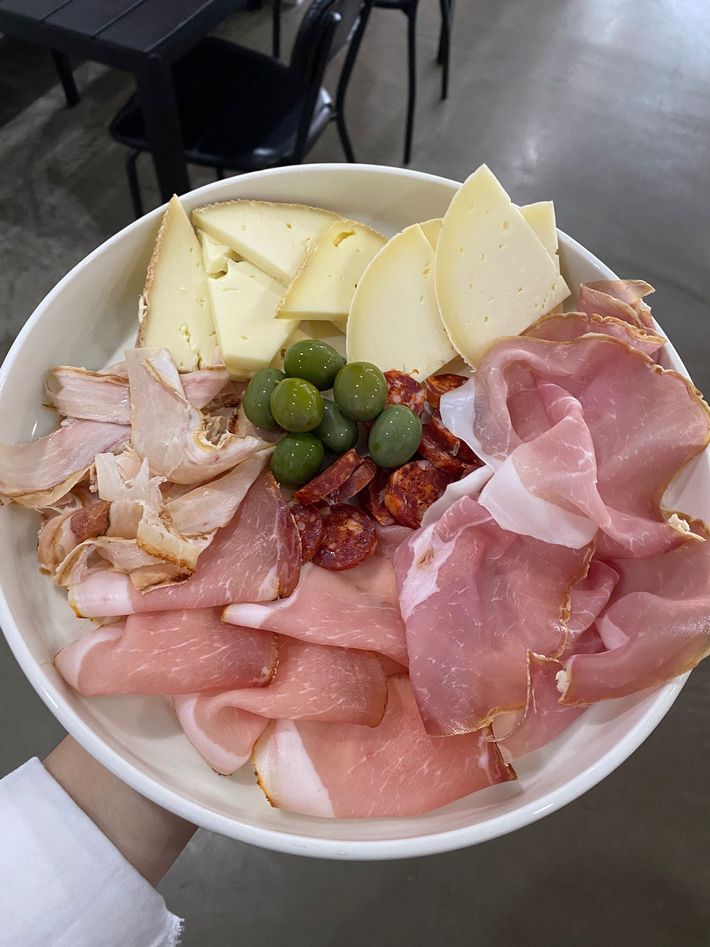Un assortimento di affettati, formaggi, olive e salsa in una ciotola, tenuta sopra un tavolino da caffè.