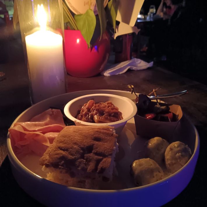 Antipasti, bevande e salumi su un tavolo all'aperto illuminato dal sole.