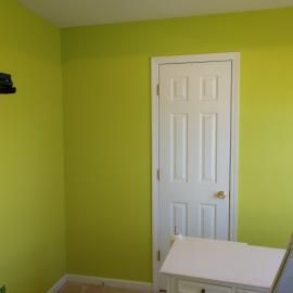 A white, six-panel door is set in a room with bright lime green walls and white trim.