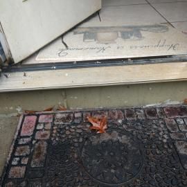 An open door reveals an entryway mat reading 