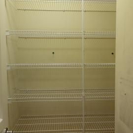 A pantry closet featuring empty white wire shelving units mounted against off-white walls.