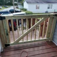 A new light-colored wooden safety gate installed on a deck stairway, viewed from the top of the stairs.