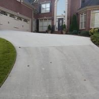 A paved driveway leads to the garage and front entrance of a two-story brick suburban house.
