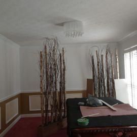 Two tall, decorative branch installations stand on either side of a table covered with a black cloth in a dining room.