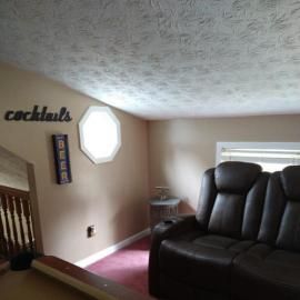 A basement room featuring a dark leather reclining sofa, a pool table, and 