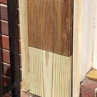 A new section of light-colored wood has been spliced onto an older, dark-stained wooden post.