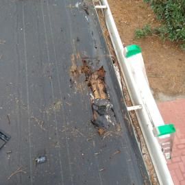 A damaged area on a black, ribbed surface next to a white railing with green accents.