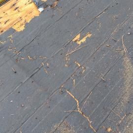 Roofing underlayment paper partially covering plywood sheathing on a construction site.
