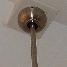 A brushed nickel ceiling fan canopy mounted flush against a white ceiling, with a single metal downrod extending downward.