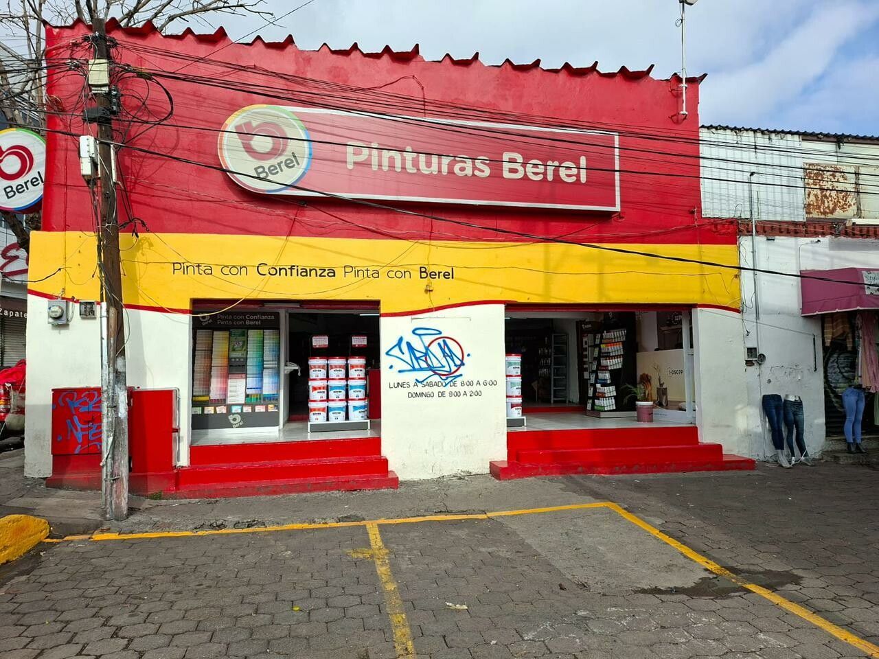 Un edificio rojo y amarillo con autos estacionados frente a él.