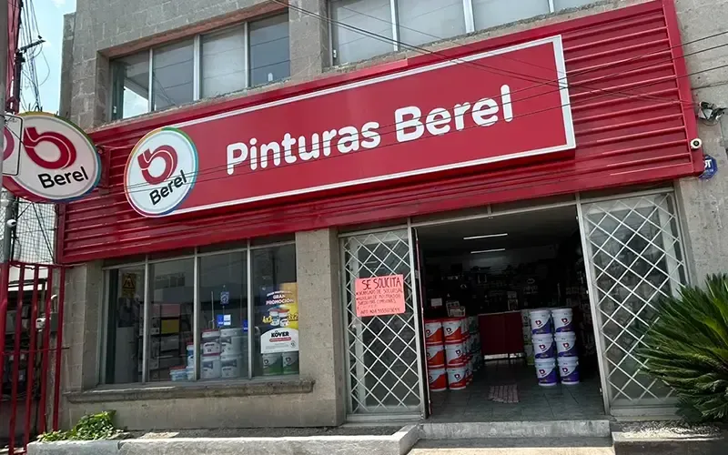 El frente de una tienda con un cartel rojo que dice pintura berel.