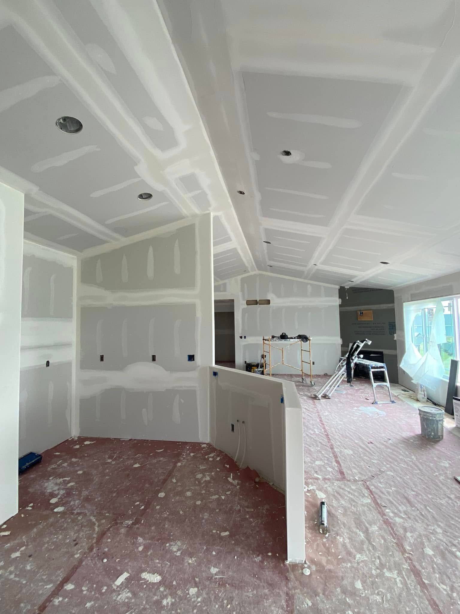 Unfinished kitchen with drywall, white cabinets, and construction debris on the floor