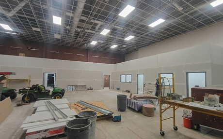 Partially renovated warehouse interior with tools, lumber, ladders, and construction materials scattered around.
