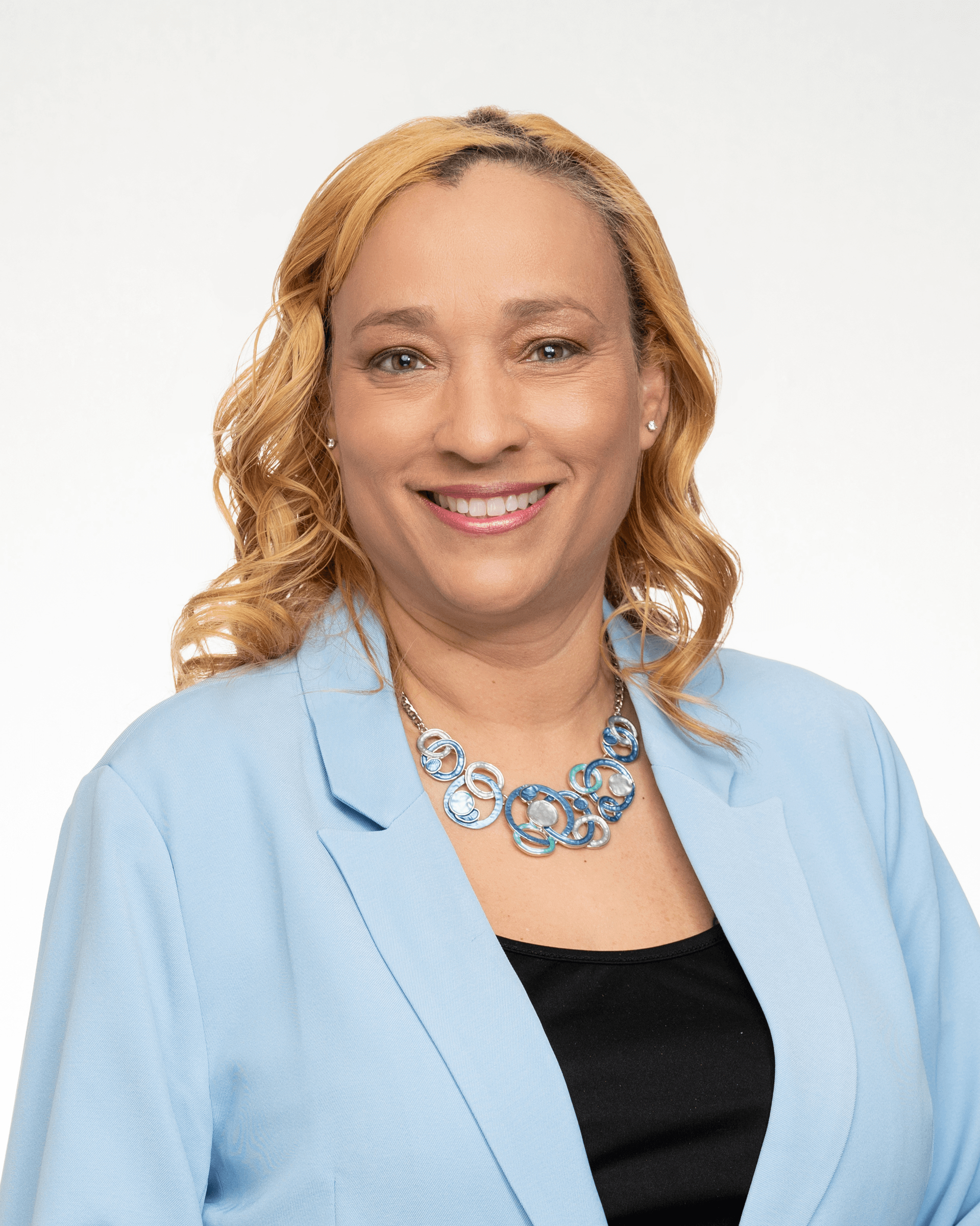 a woman wearing a blue jacket and a necklace is smiling for the camera .