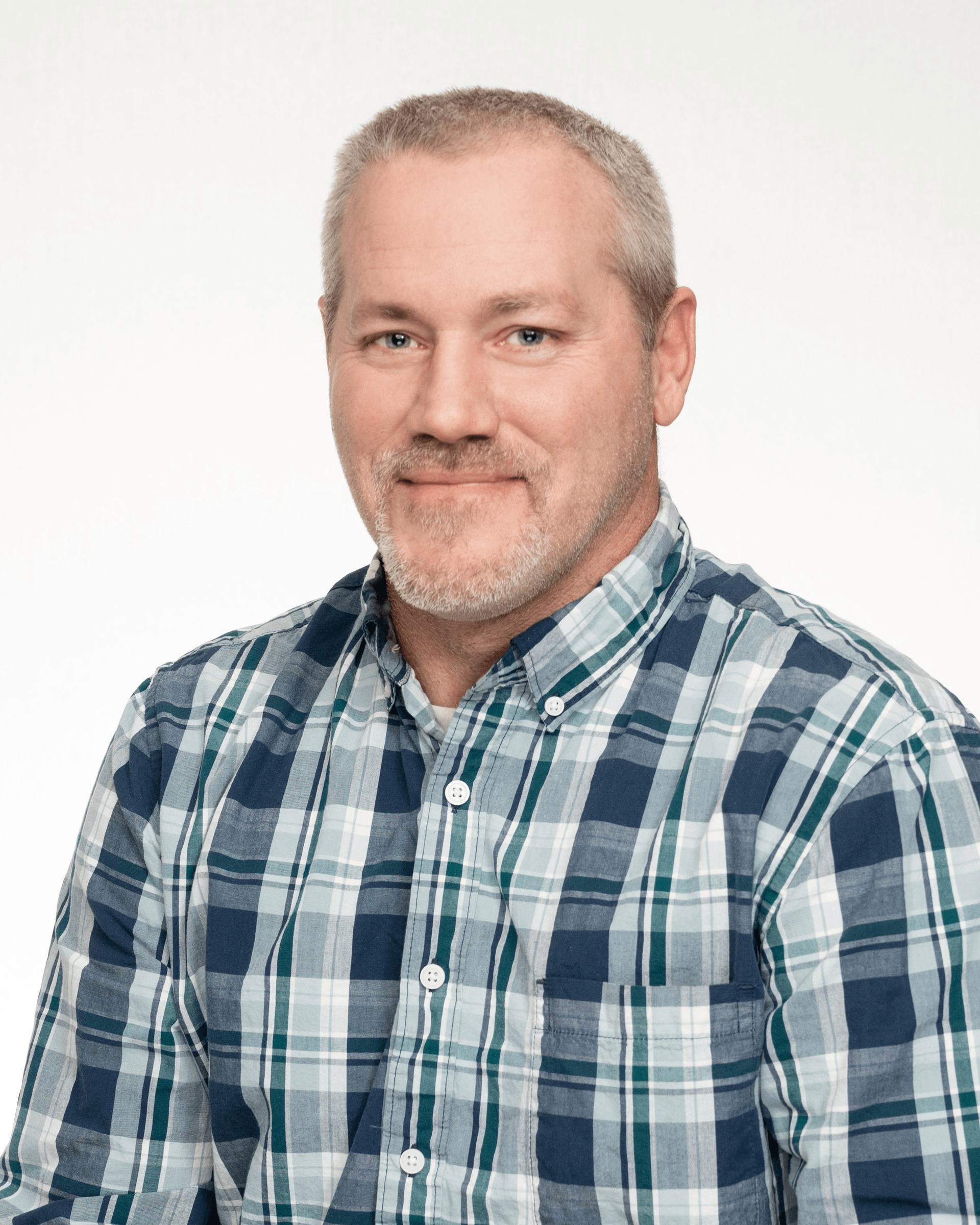 a man in a plaid shirt is smiling for the camera .