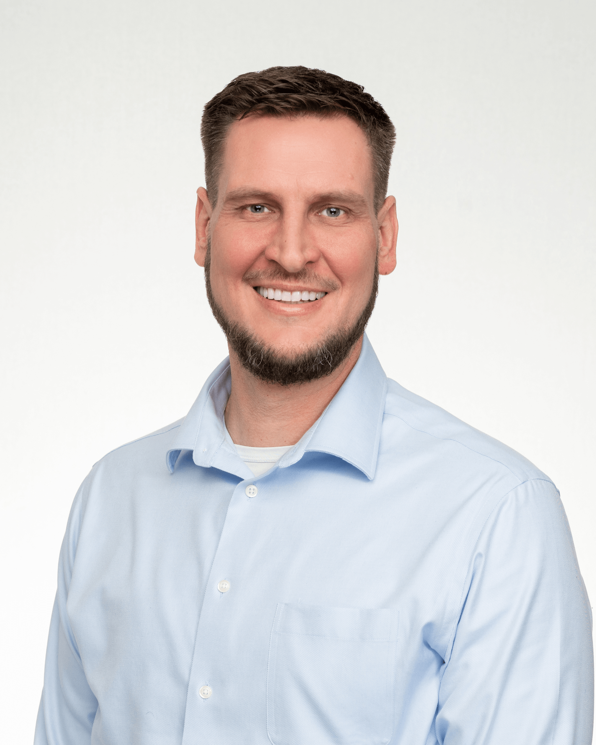 a man with a beard is wearing a blue shirt and smiling for the camera .