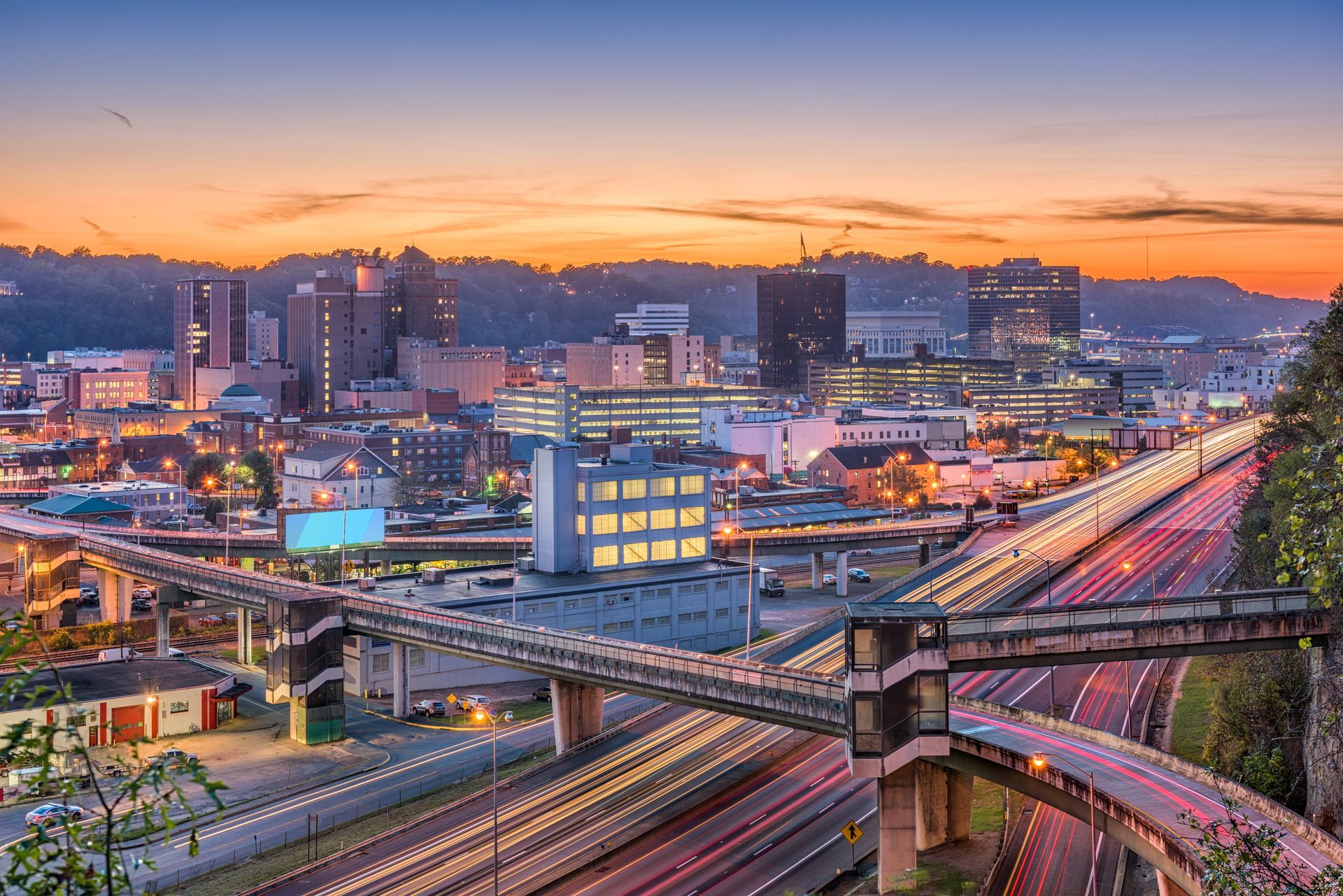 an aerial view of a city at sunset with a highway in the foreground .