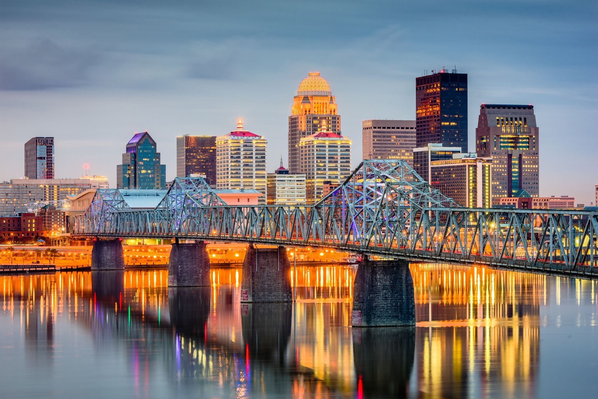 a bridge over a body of water with a city skyline in the background .
