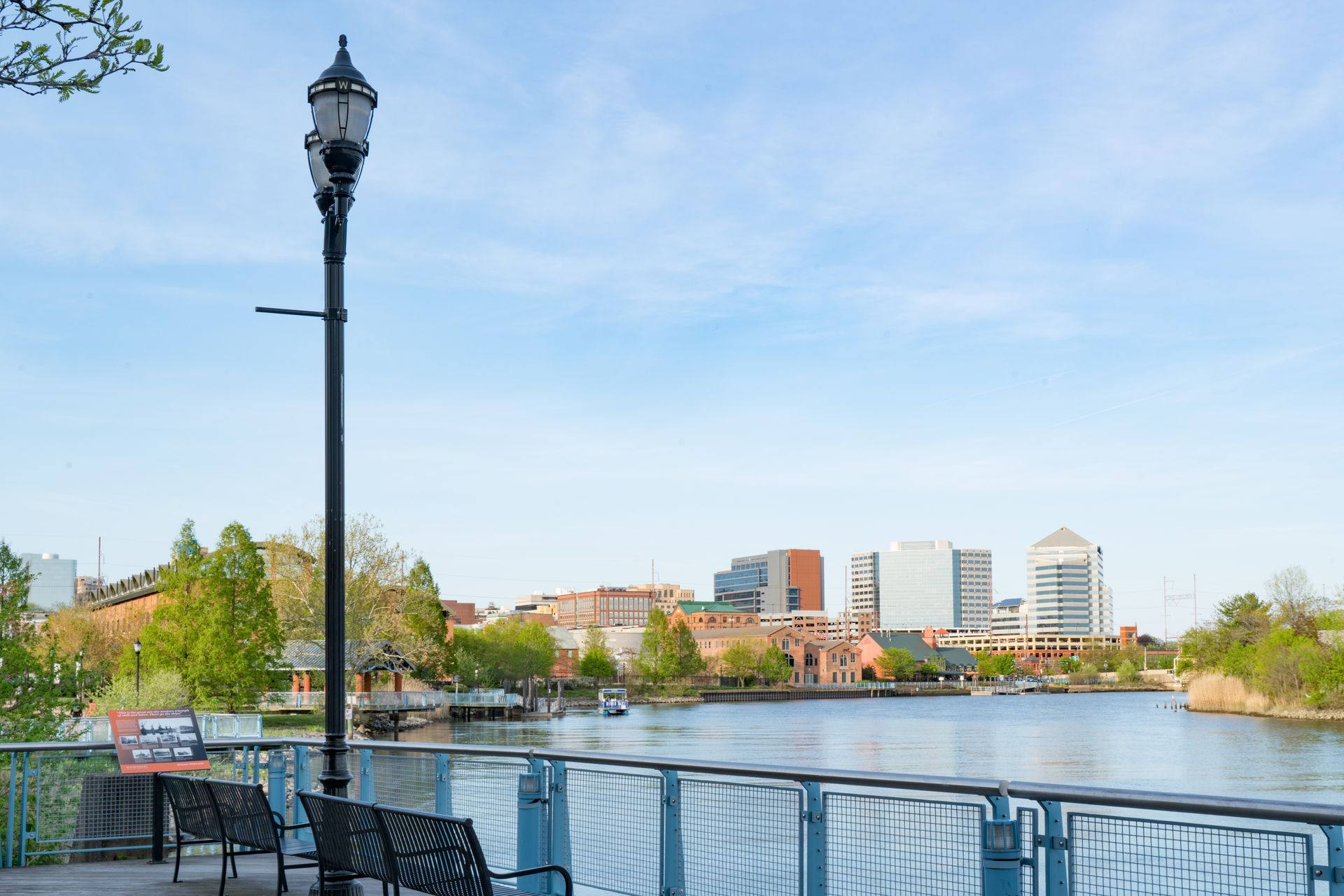 a park bench sitting next to a lake with a city skyline in the background .