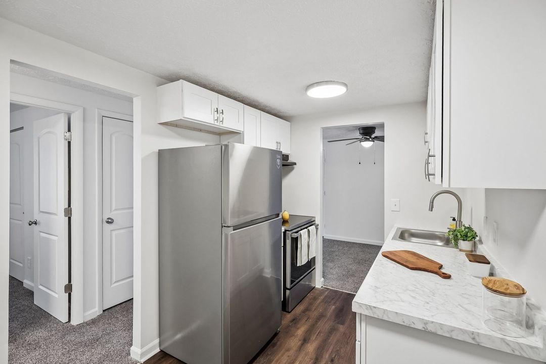 White kitchen with brick wall, wooden counters, white cabinets, and plants.