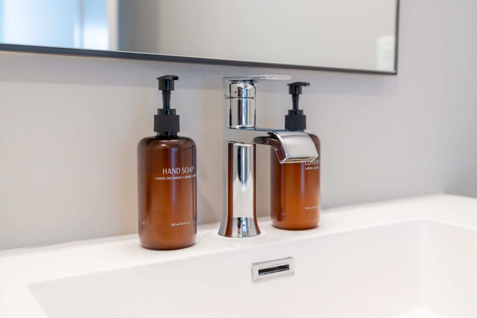 Amber soap dispensers beside a chrome faucet on a white bathroom sink