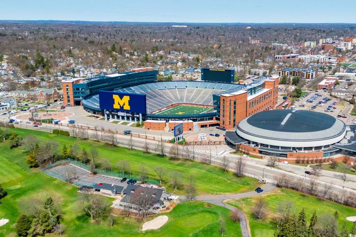 Aerial view of Michigan Stadium on a campus surrounded by trees and city streets